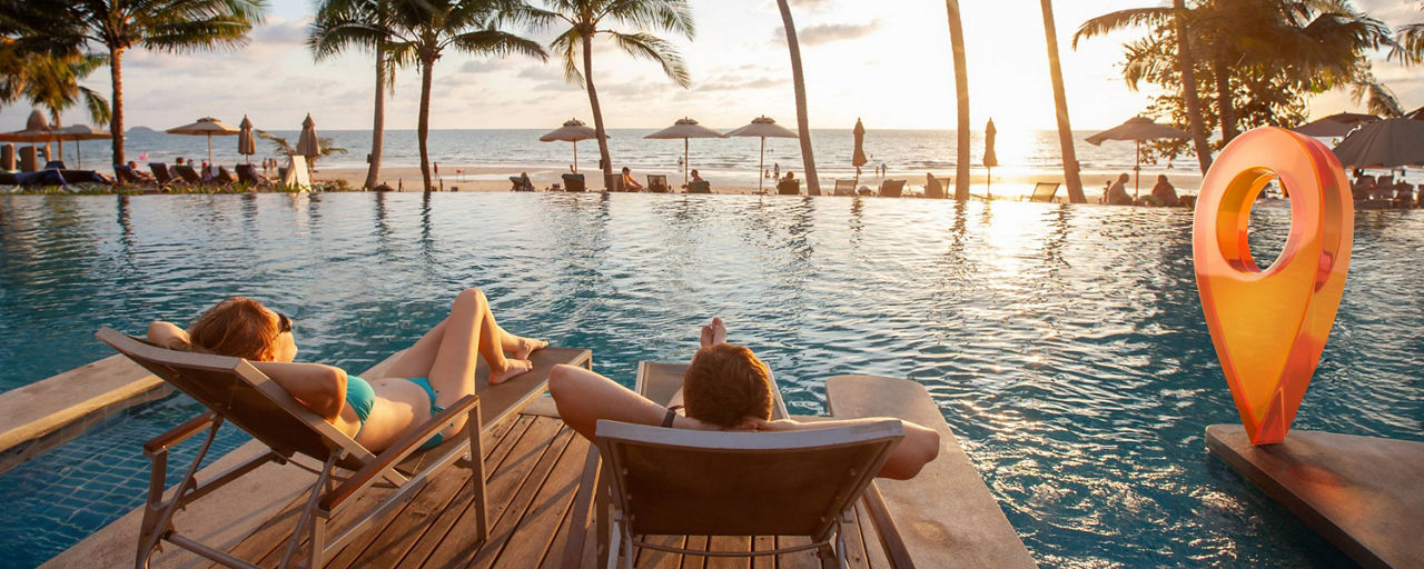 Paar am Pool entspannt auf Sonnenliegen