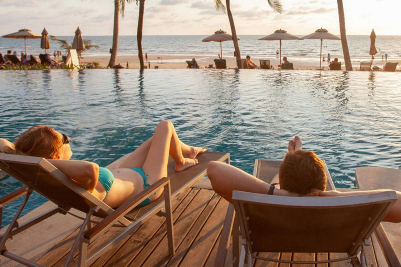 Paar am Pool entspannt auf Sonnenliegen