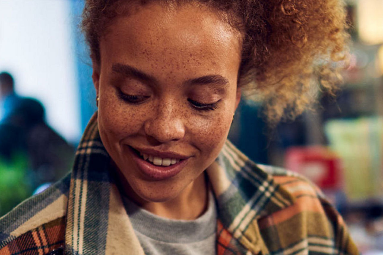 Frau mit Hund betreibt Banking am Smartphone auf einer Bank im Garten.