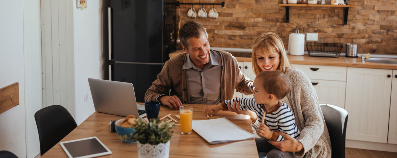 Familie - Vater, Mutter, Kind sitzen am Küchentisch.