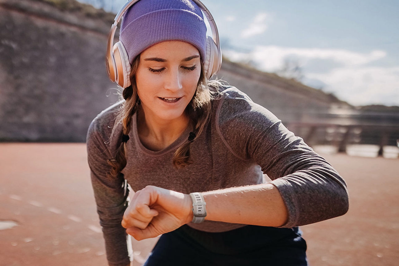 Junge Frau beim Sport schaut auf Ihre neue SmartWatch