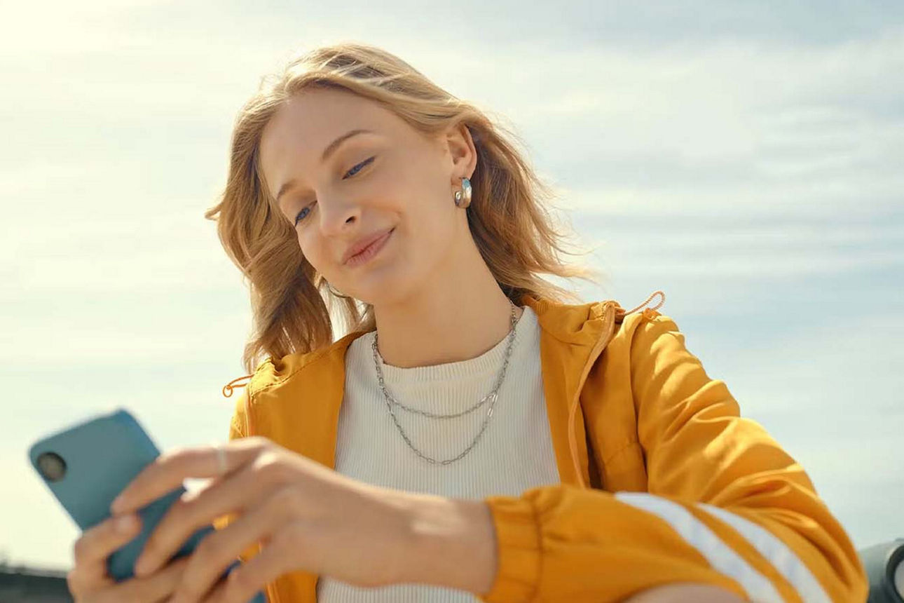 Junge Frau sitzt draußen und ist am Smartphone