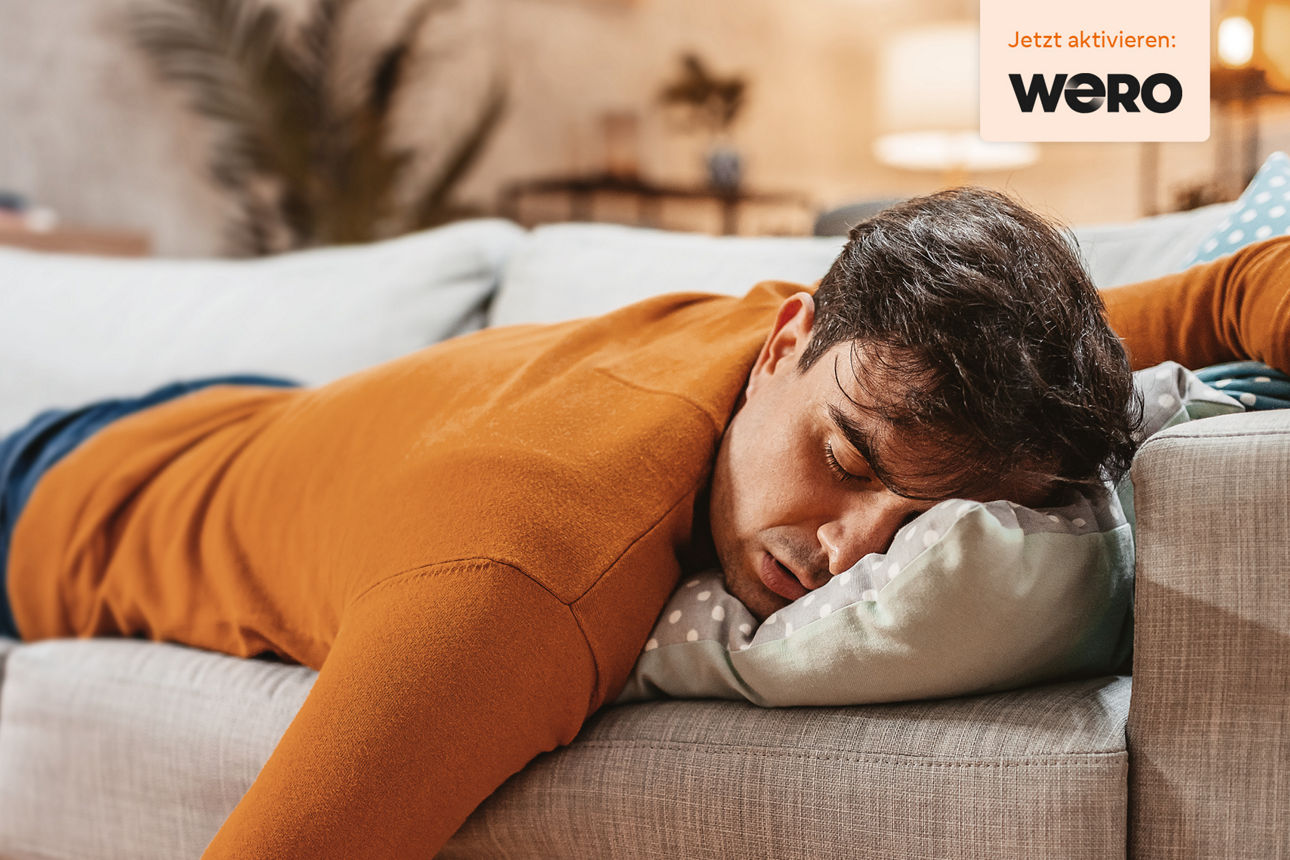 Junger Mann liegt verschlafen auf dem Sofa