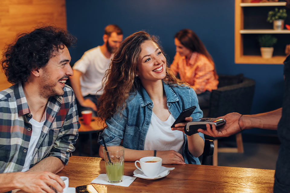 Pärchen im Café bezahlt kontaktlos mit dem Smartphone