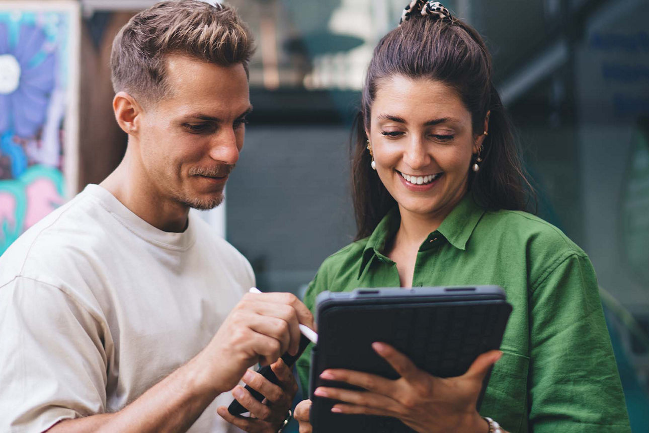 Junge Frau und Mann zeigen sich etwas auf einem Tablet