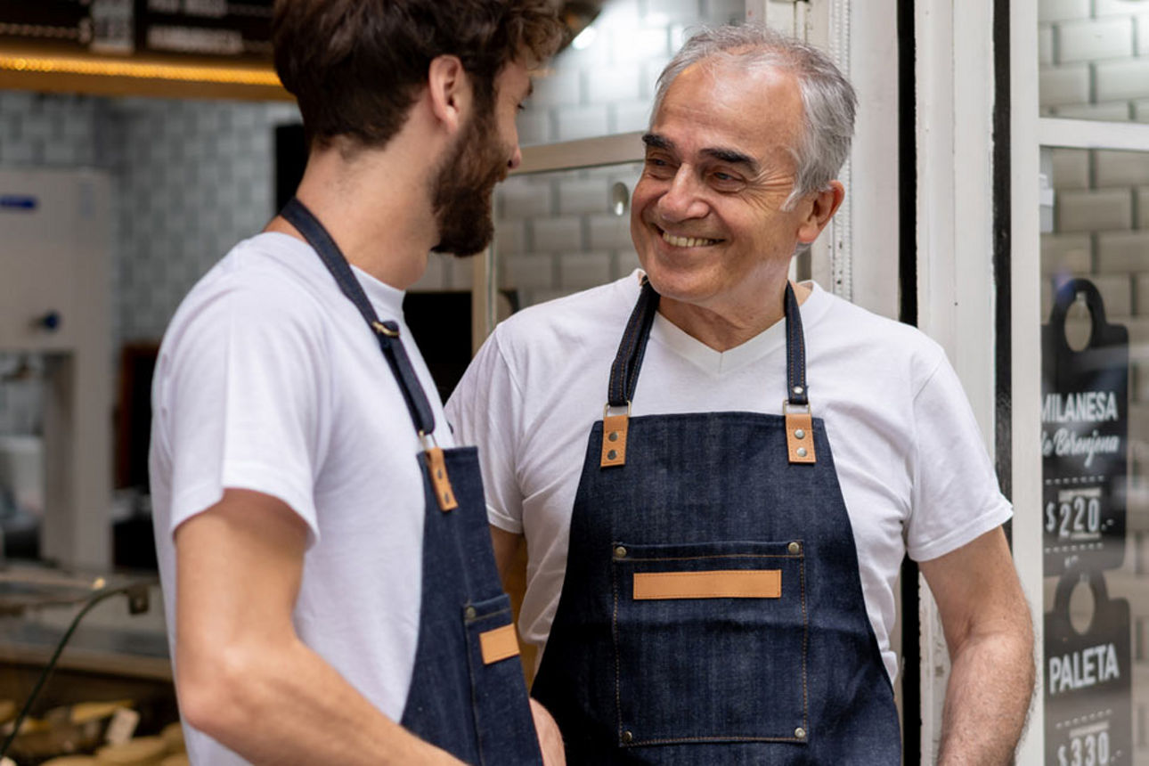 Zwei Männer mit Schürzen führen ein freundliches Gespräch