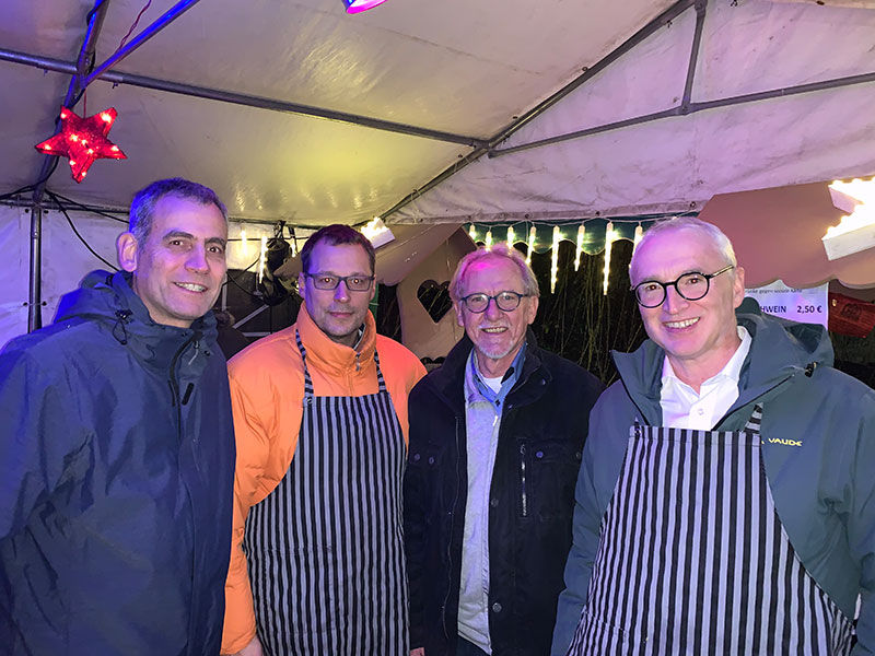 4 glückliche Männer trinken Glühwein und haben eine gute Zeit zusammen
