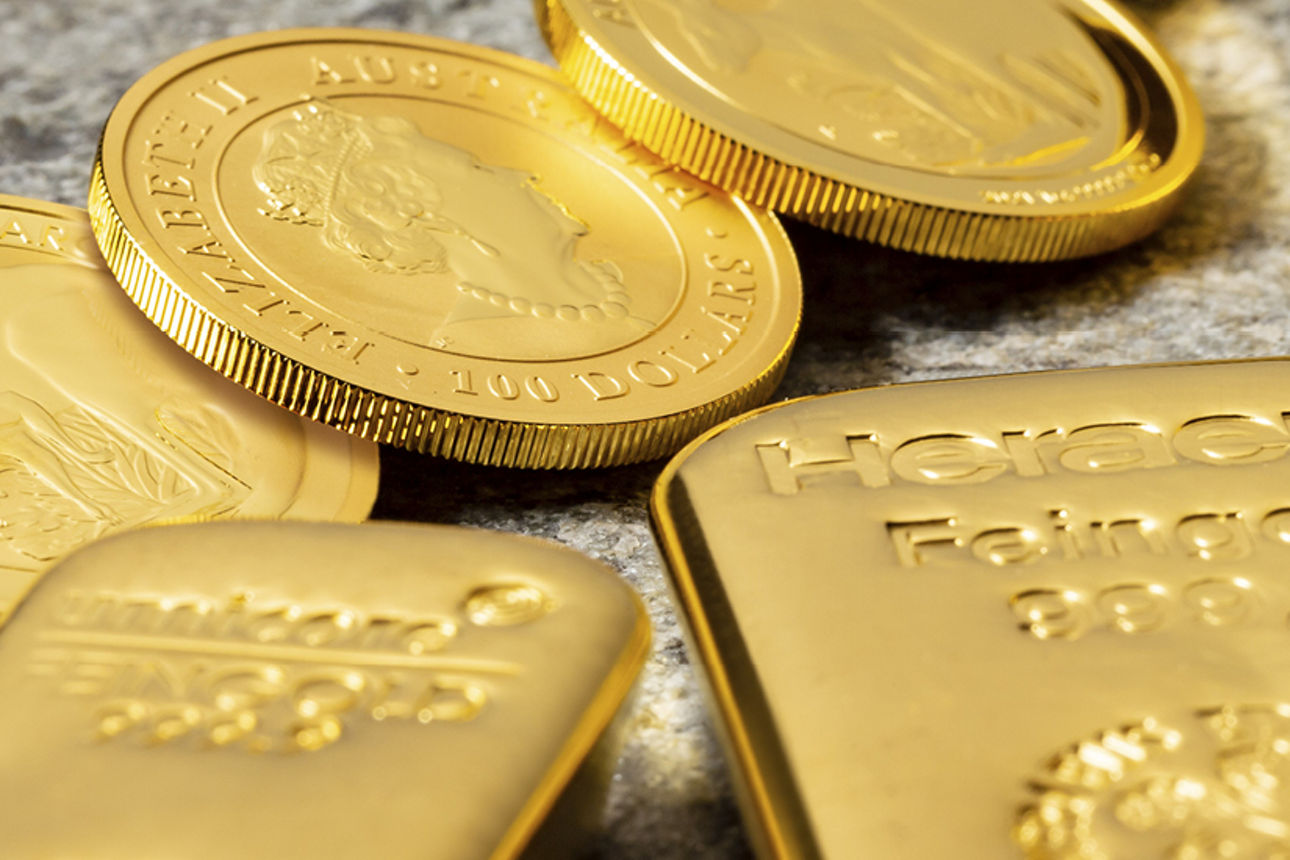 Es liegen drei Gold Münzen und zwei Goldbarren auf einem Stein