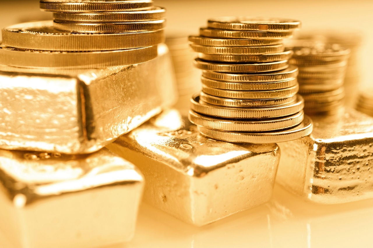 Goldbarren und Goldmünzen gestapelt übereinander