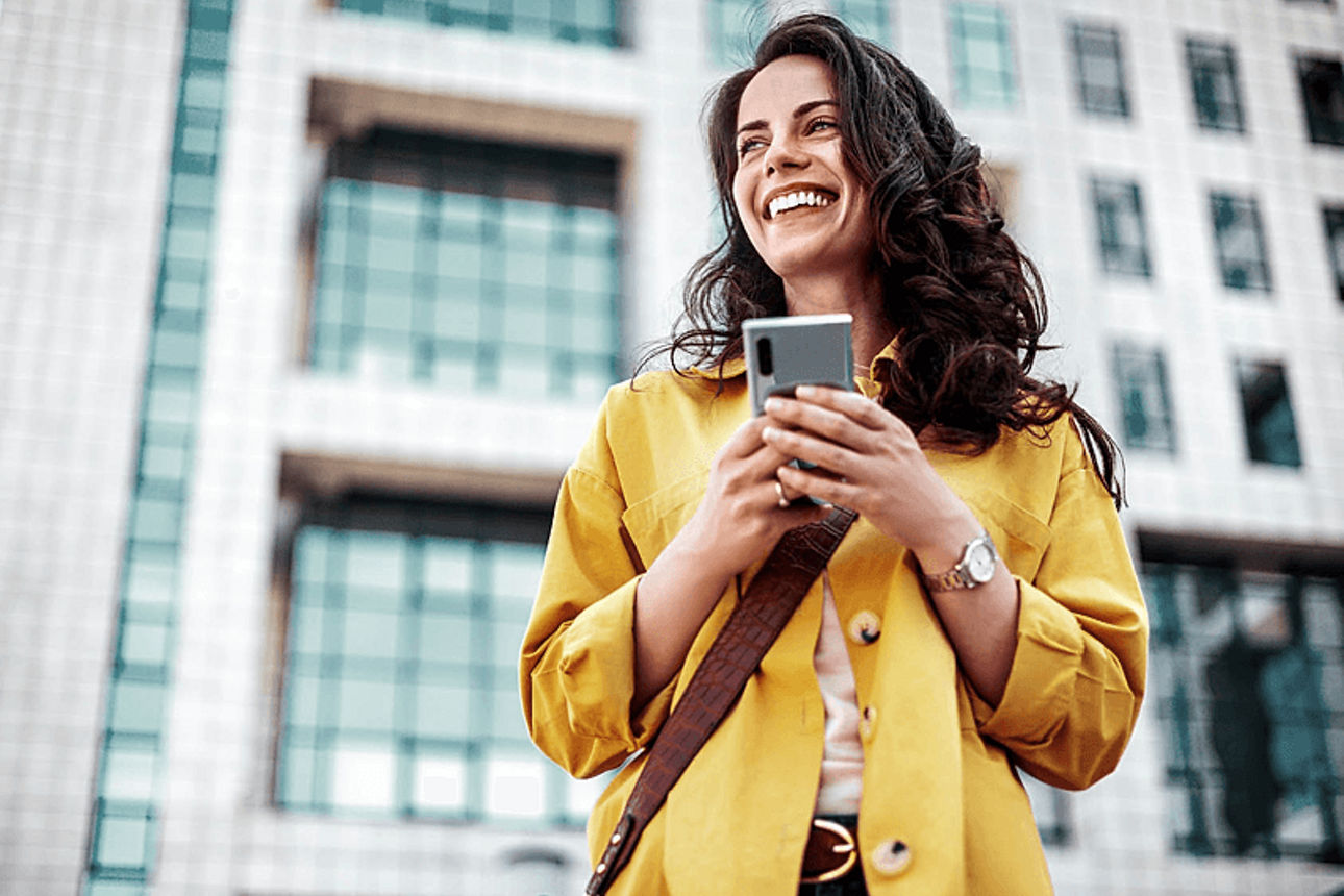 Eine Frau lächelt mit einem Smartphone in der Hand