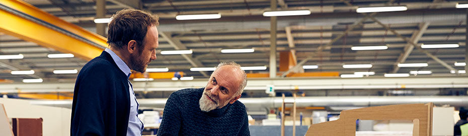 Vater und Sohn stehen an einem Tisch in einer Gewerbehalle