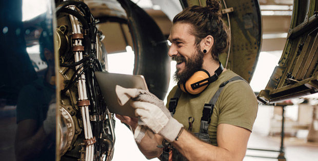 Ein junger Mann steht in einer Werkstatt und hat Spaß an der Arbeit