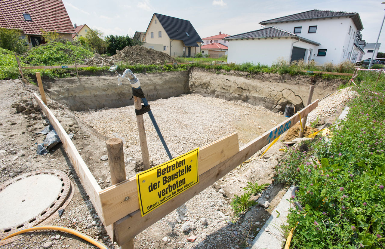 Baugrube mit hölzender Absperrung umgeben von Rasen