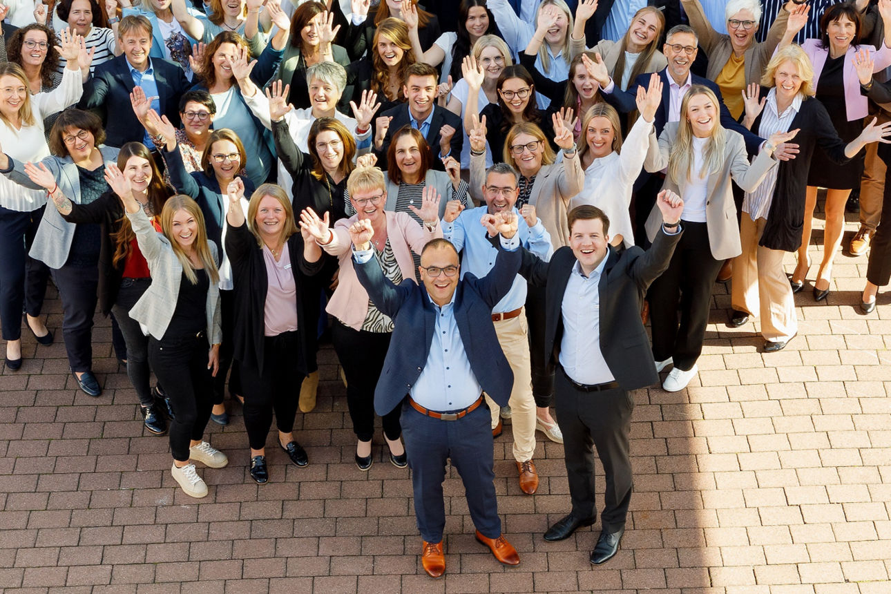 Gruppe von Mitarbeitern, die in Form eines Herzen gemeinsam stehen
