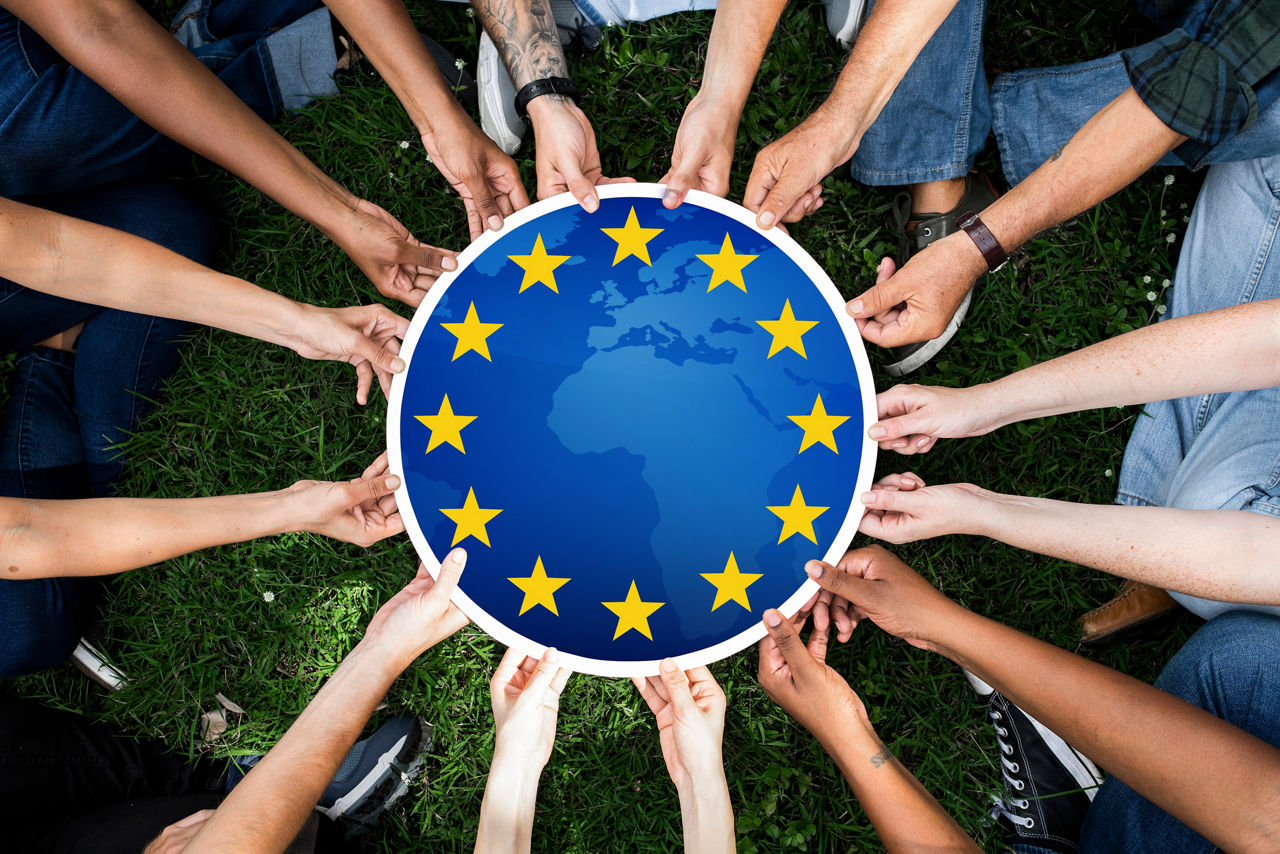 Ganz viele Hände halten eine runde Scheide mit der Europafahne