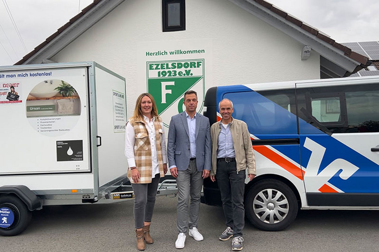 Eine Frau und zwei adrett gekleidete Männer lächeln