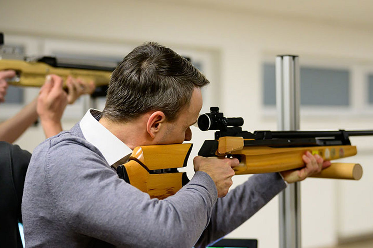 Mann mit Gewehr auf Schießstand zielend