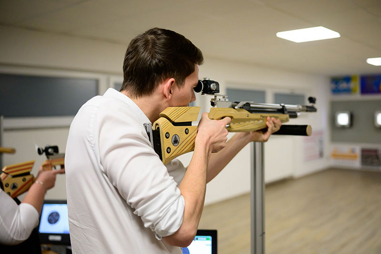 Mann mit Gewehr auf Schießstand zielend