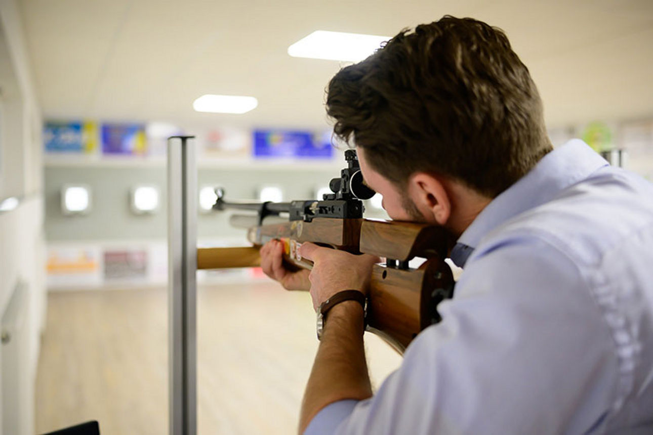 Mann mit Gewehr auf Schießstand zielend