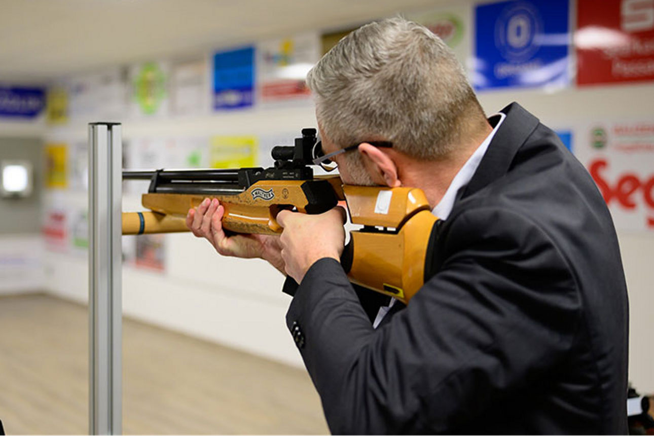 Mann mit Gewehr auf Schießstand zielend