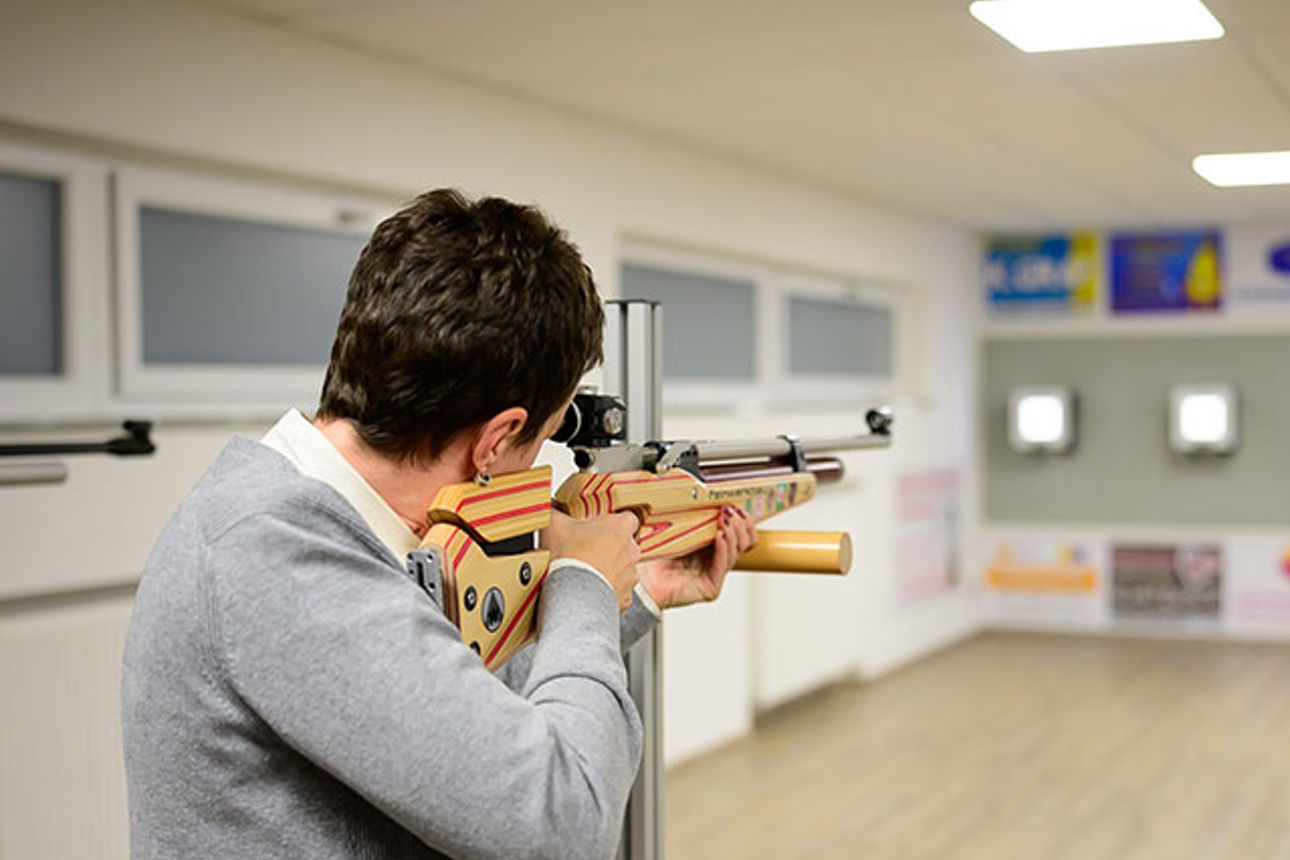 Mann mit Gewehr auf Schießstand zielend