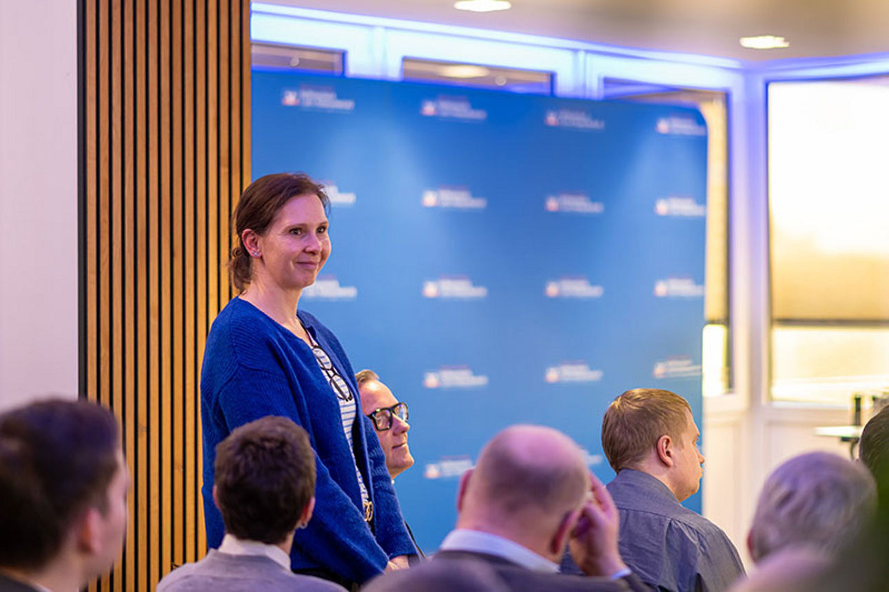 Frau steht zwischen sitzenden Menschen