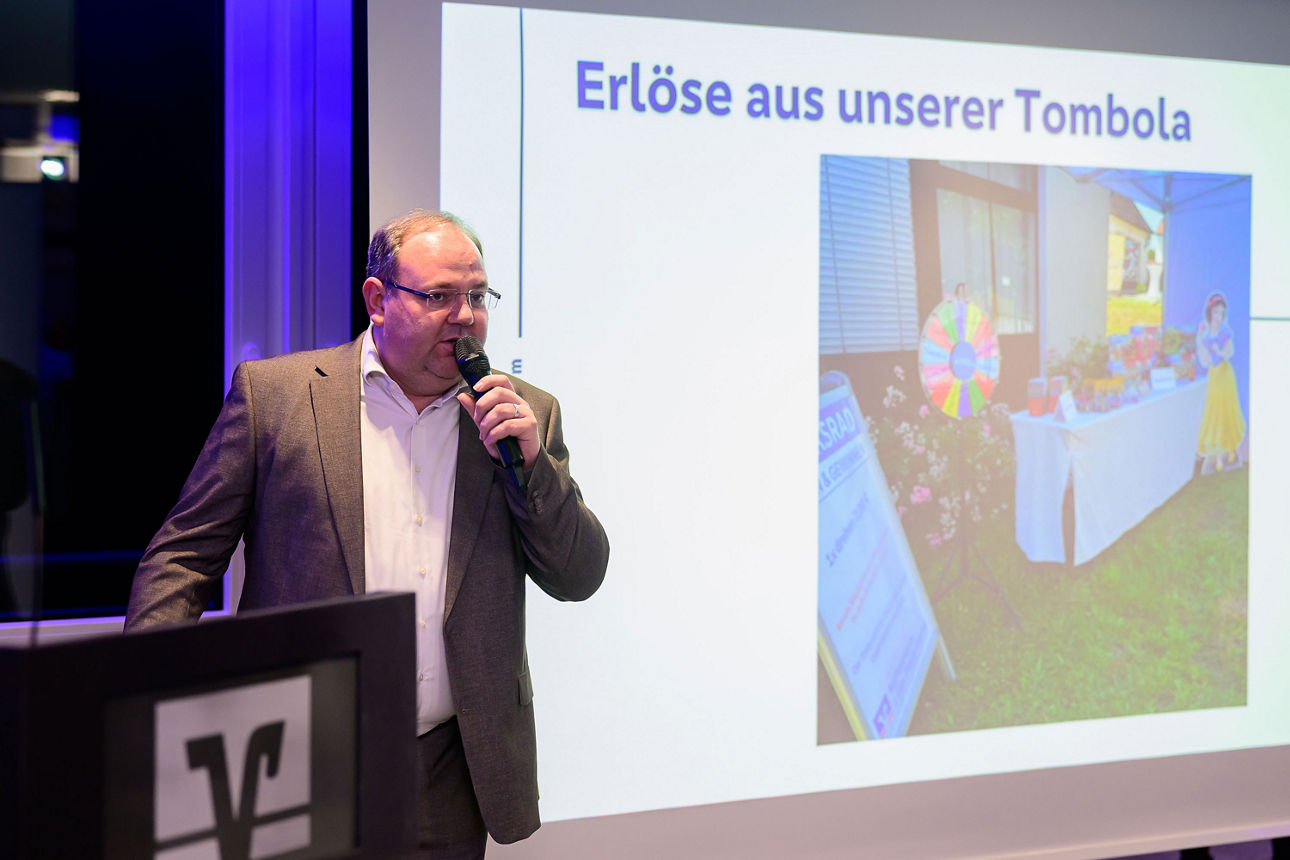 Mann mit Mikrofon und Leinwand im Hintergrund