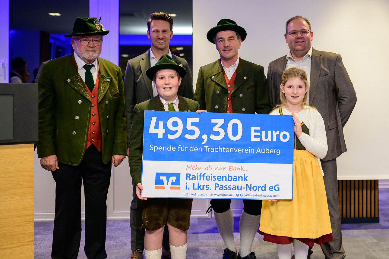 4 Männer, ein Mädchen und ein Junge halten einen Scheck mit 495,30 Euro