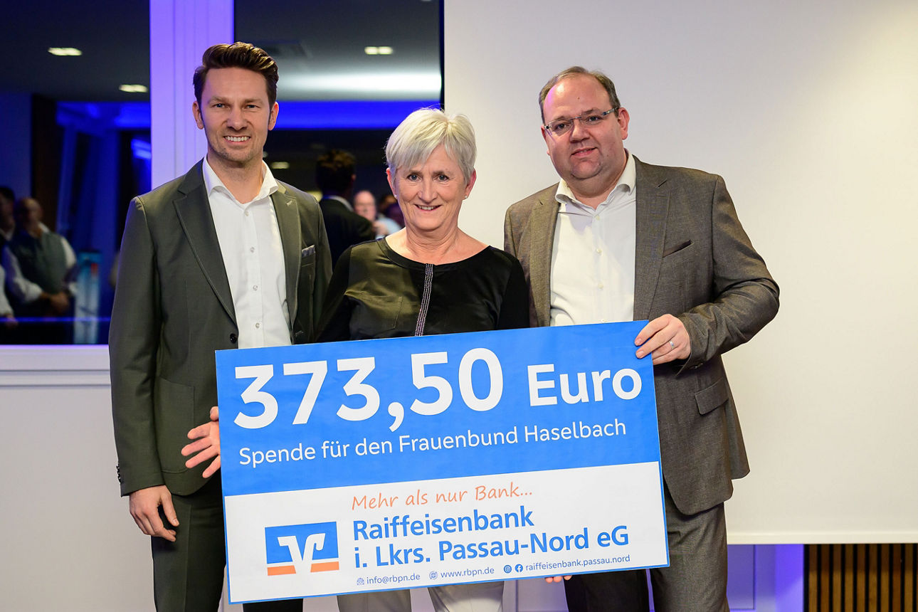 Eine Frau und zwei Männer halten einen Spendenscheck mit 373,50 Euro in der Hand