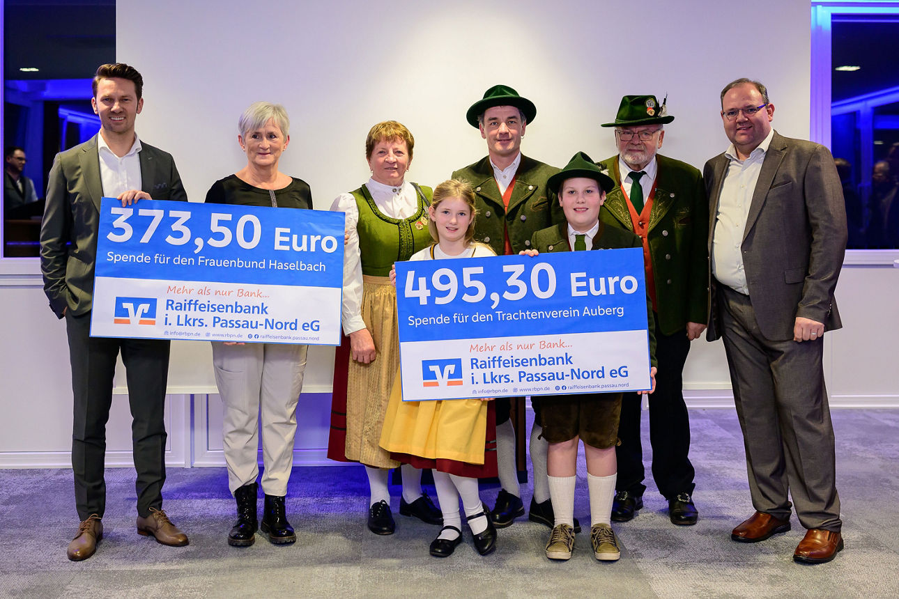 Zwei Frauen, vier Männer, ein Mädchen und ein Junge halten jeweils einen Scheck mit 373,50 Euro und 495,30 Euro in der Hand