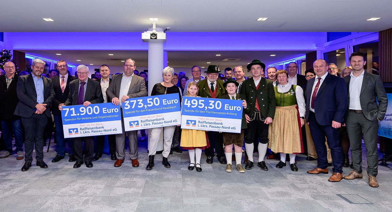Ein Gruppenfoto der Spendenübergabe in einem Sall mit blauer Beleuchtung.