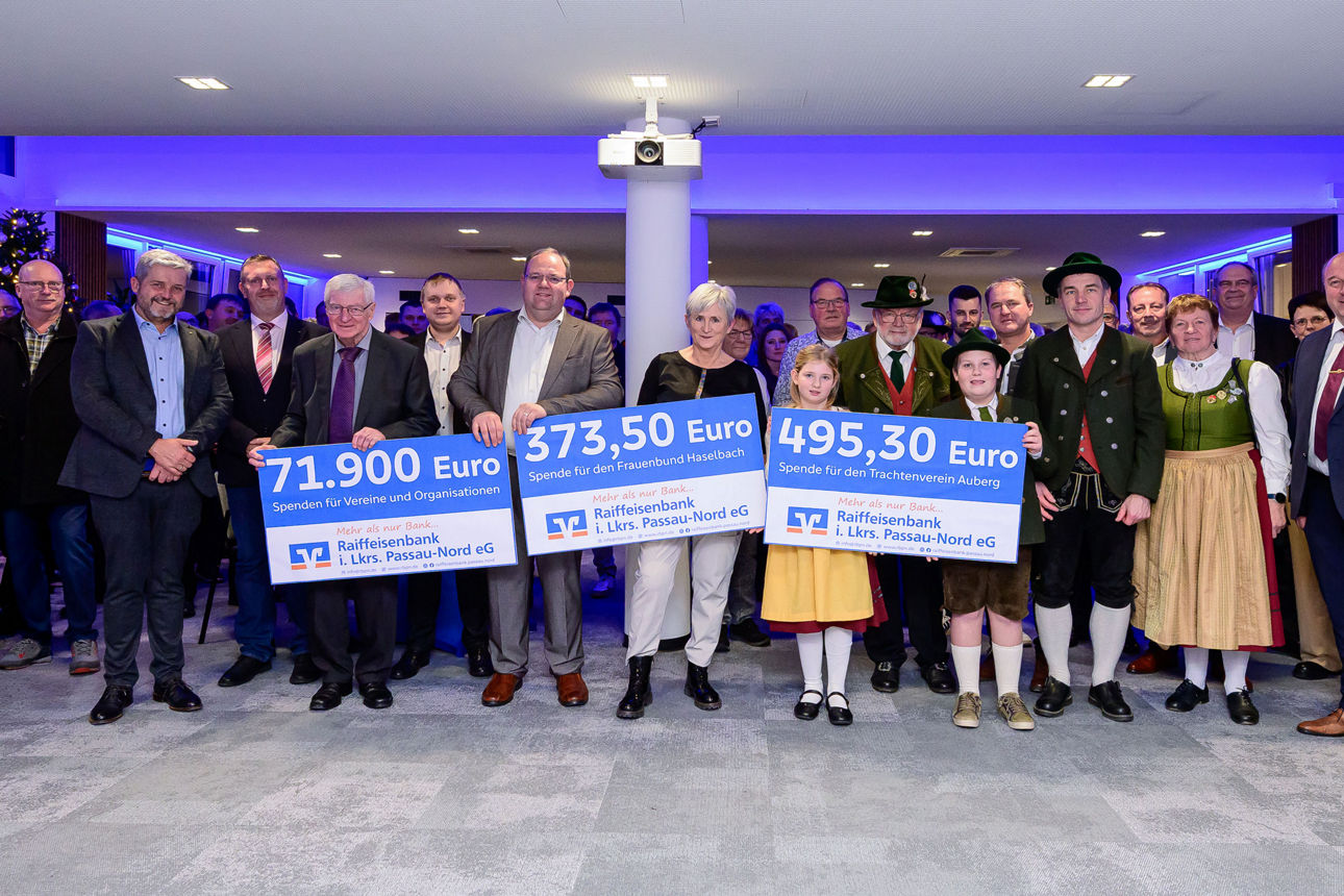 Ein Gruppenfoto der Spendenübergabe in einem Sall mit blauer Beleuchtung.