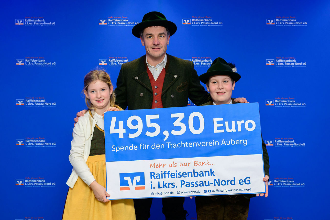Ein Mädchen, ein Junge und ein Mann in Tracht halten einen Scheck mit 495,30 Euro in der Hand