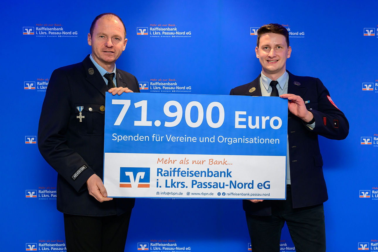 2Männer halten einen Spendenscheck mit 71.900 Euro in der Hand