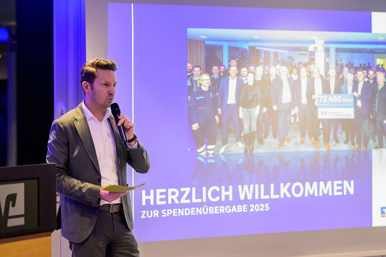 Mann mit Mikrofon und Leinwand im Hintergrund