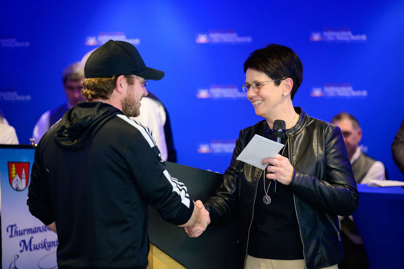 ein Mann erhält per Handschlag ein Kuvert von einer Frau.