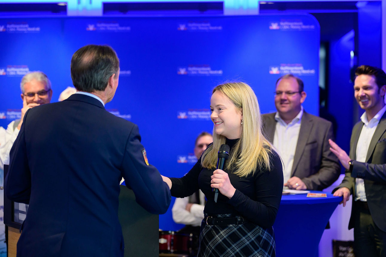ein Mann erhält per Handschlag ein Kuvert von einer Frau.