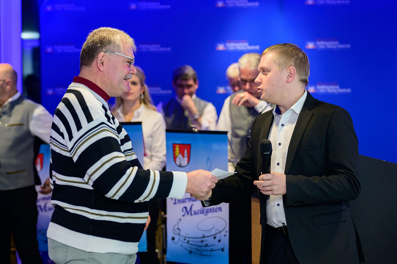 ein Mann erhält per Handschlag ein Kuvert von einem Mann.