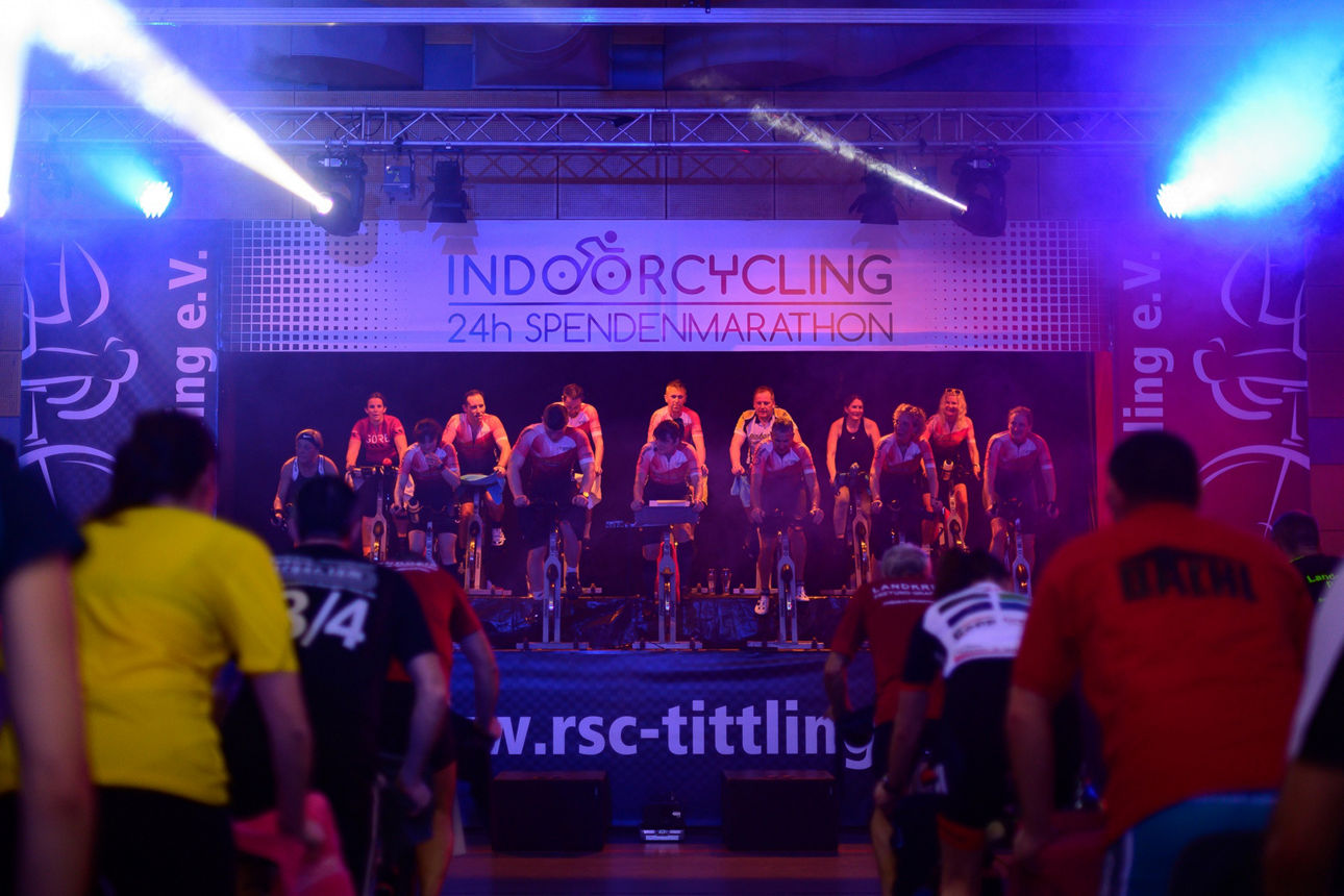 Gruppe von Menschen, die auf einer Bühne Indoor-Fahrrad fahren