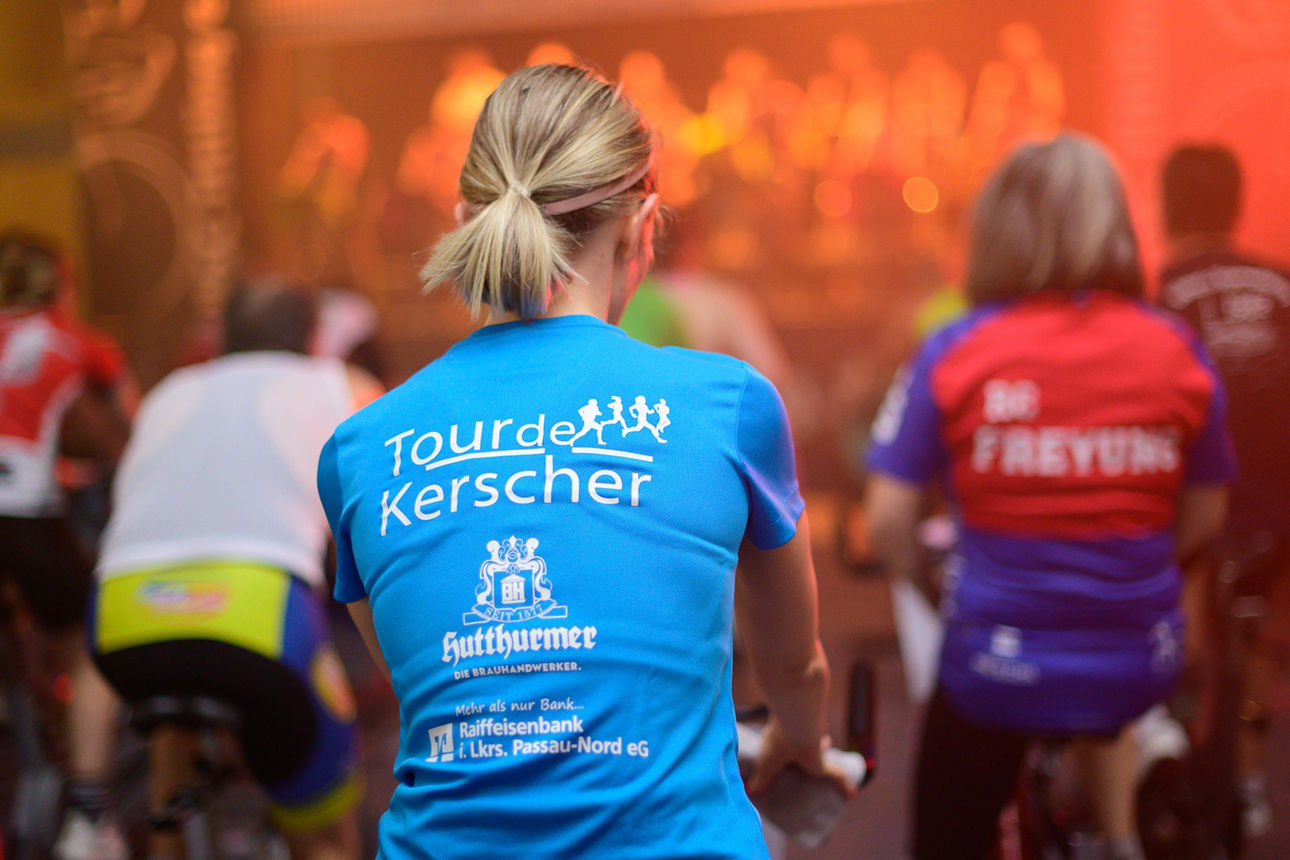 Frau von hinten auf Indoor-Fahrrad in Gruppe