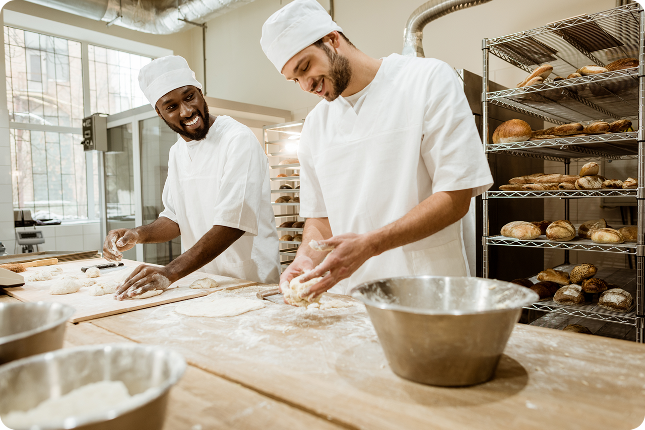 Zwei Bäcker stehen in der Backstube und backen