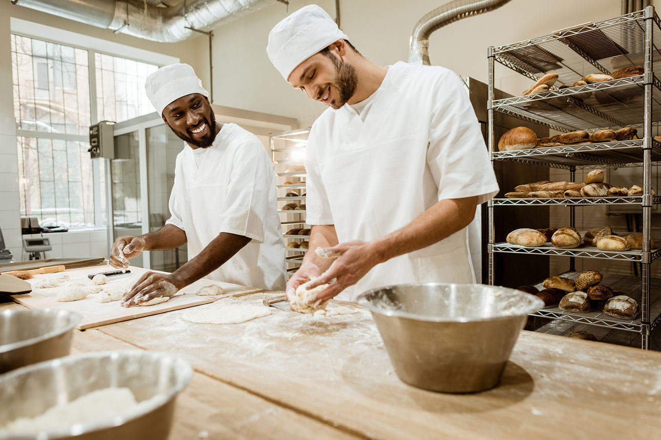 Zwei Bäcker stehen in der Backstube und backen