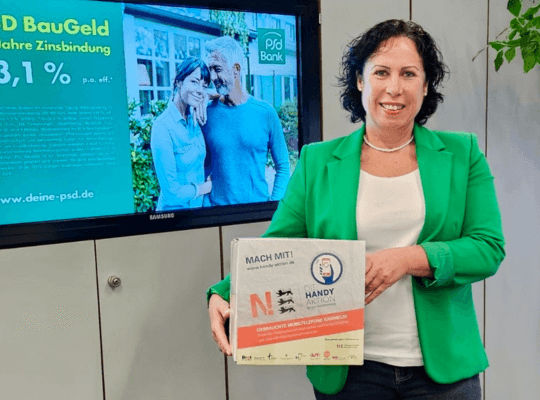 Frau mit Handy-Sammelbox steht vor einem Monitor