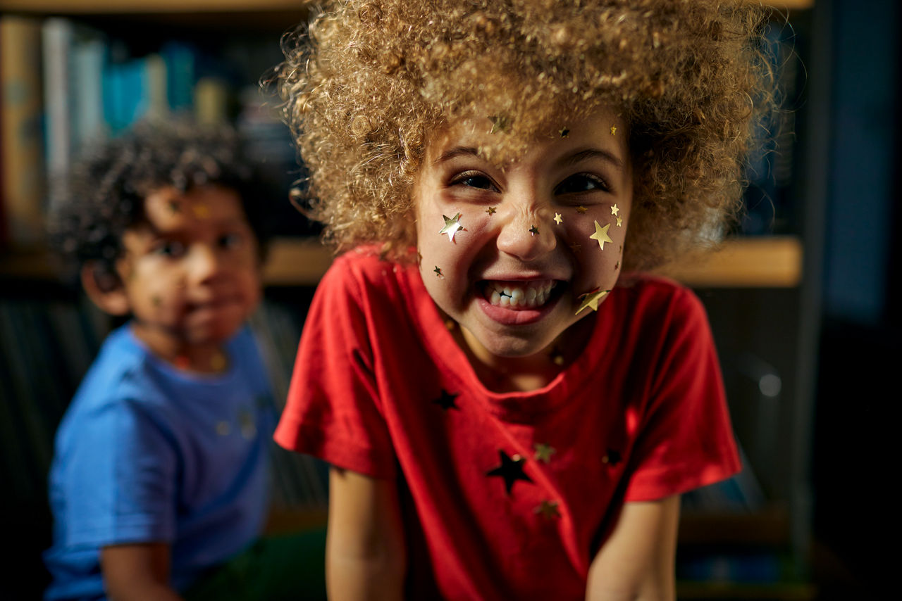 Zwei kleine Kinder, das Mädchen hat goldener Sterne auf Gesicht und Kleidung. 