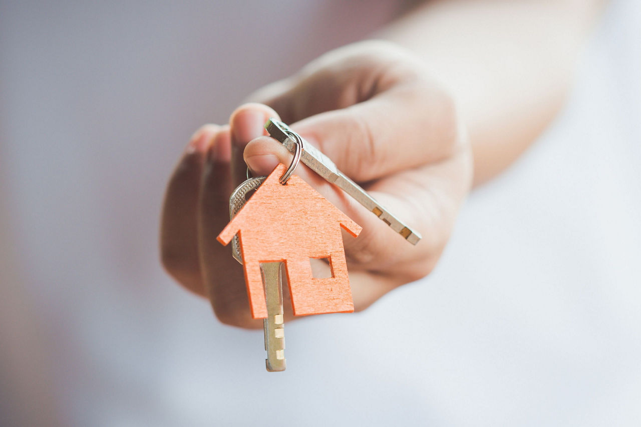 Hand hält Schlüsselanhänger in Form eines Hauses
