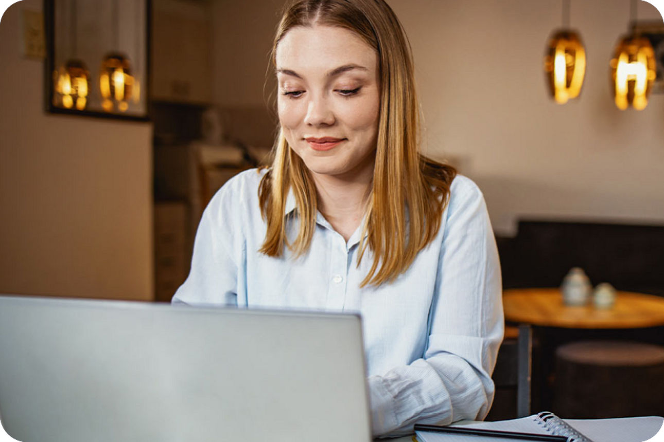 Person sitzt im Wohnzimmer bei warmen Licht am Laptop 