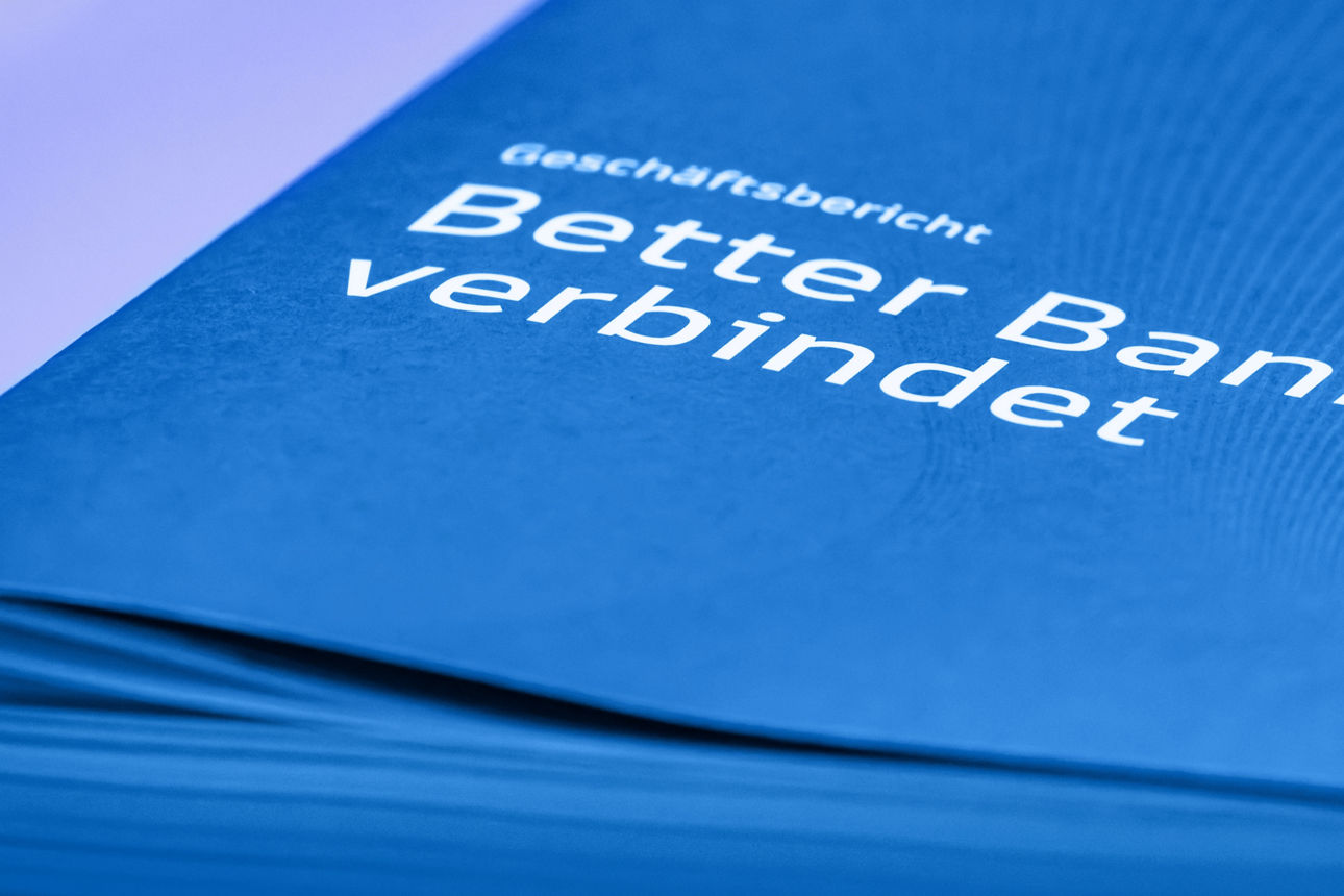 Blaue Mappe liegt auf einem Tisch. Auf der Mappe steht Better Banking verbindet.