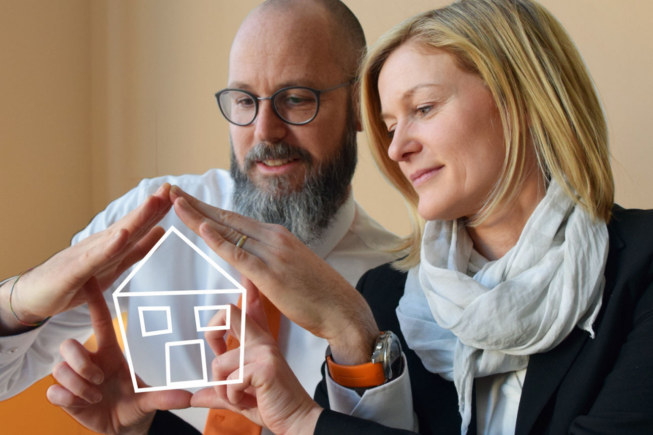 Banner mit dem Claim "Auch beim Verkauf Ihrer Immobilie sind wir eine sichere Bank" und illustrierter Hand, die ein Haus hält