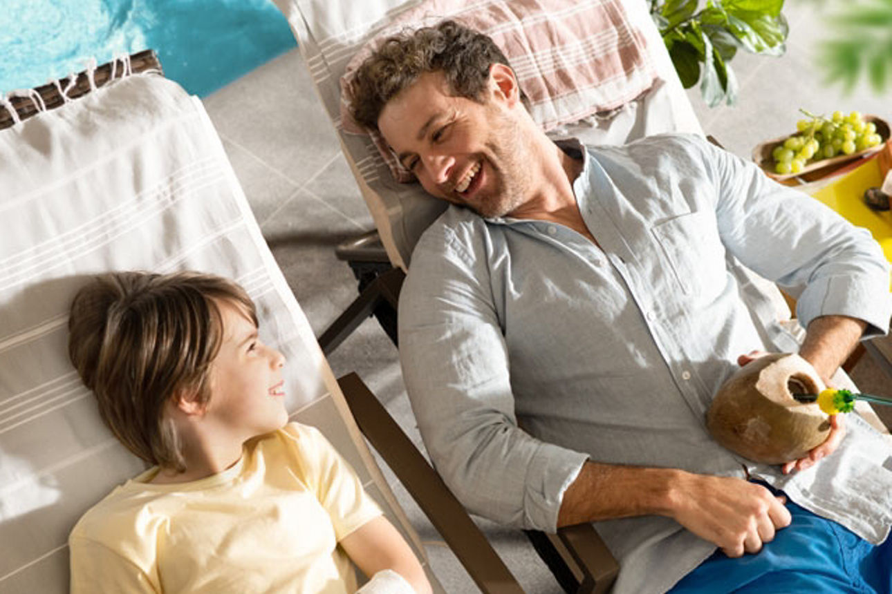 Vater und Sohn liegen auf einer Sonnenliege im Urlaub