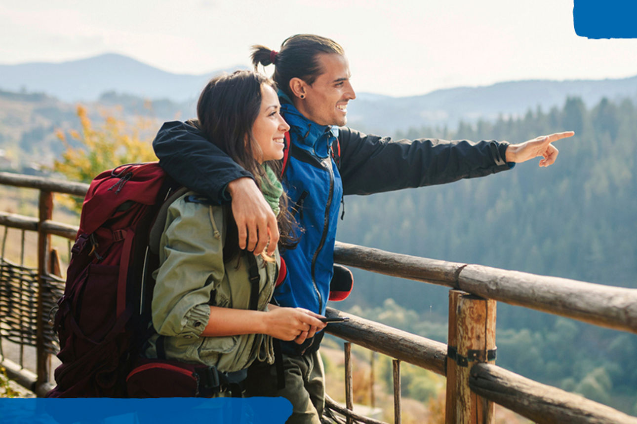 Personen stehen an einem Geländer mit Blick auf Berge; daneben ein Hinweis: 0,5 % Zinsvorteil für nachhaltige Investitionen.